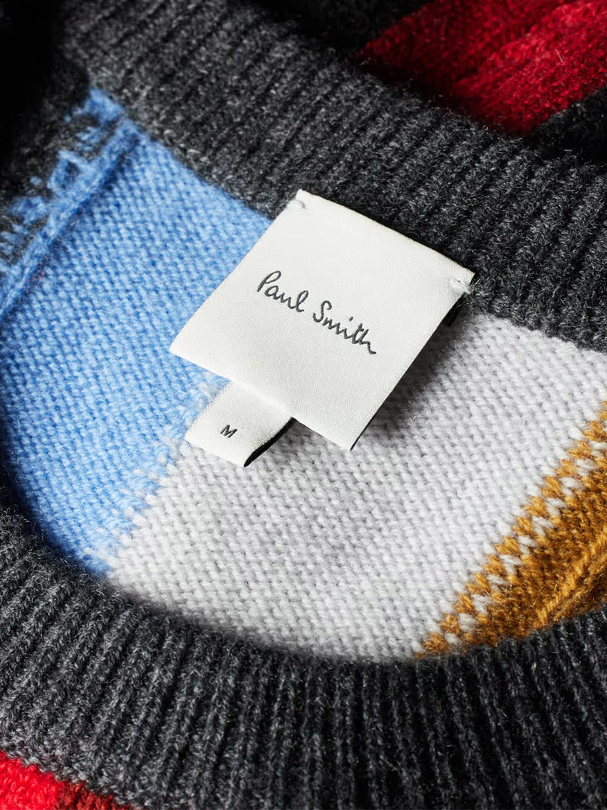Close-up of the collar on a Paul Smith Cashmere-Blend Signature Stripe Sweater in Multi, showing a white "Paul Smith" label and size "M" tag on the colorful knit.