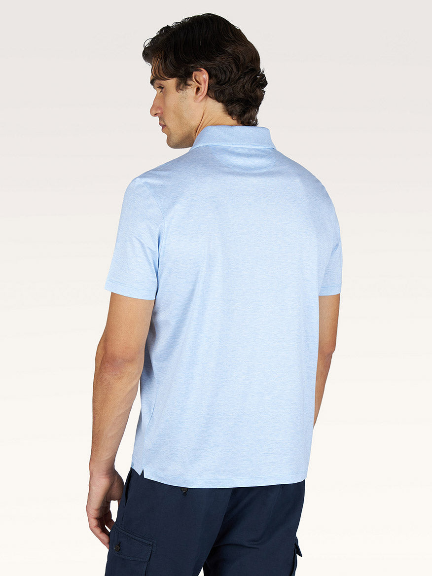 A man with brown hair stands facing away from the camera, wearing a Paul & Shark Polo Jersey Shirt With Linen Details in Cerulean and dark blue shorts against a plain background.