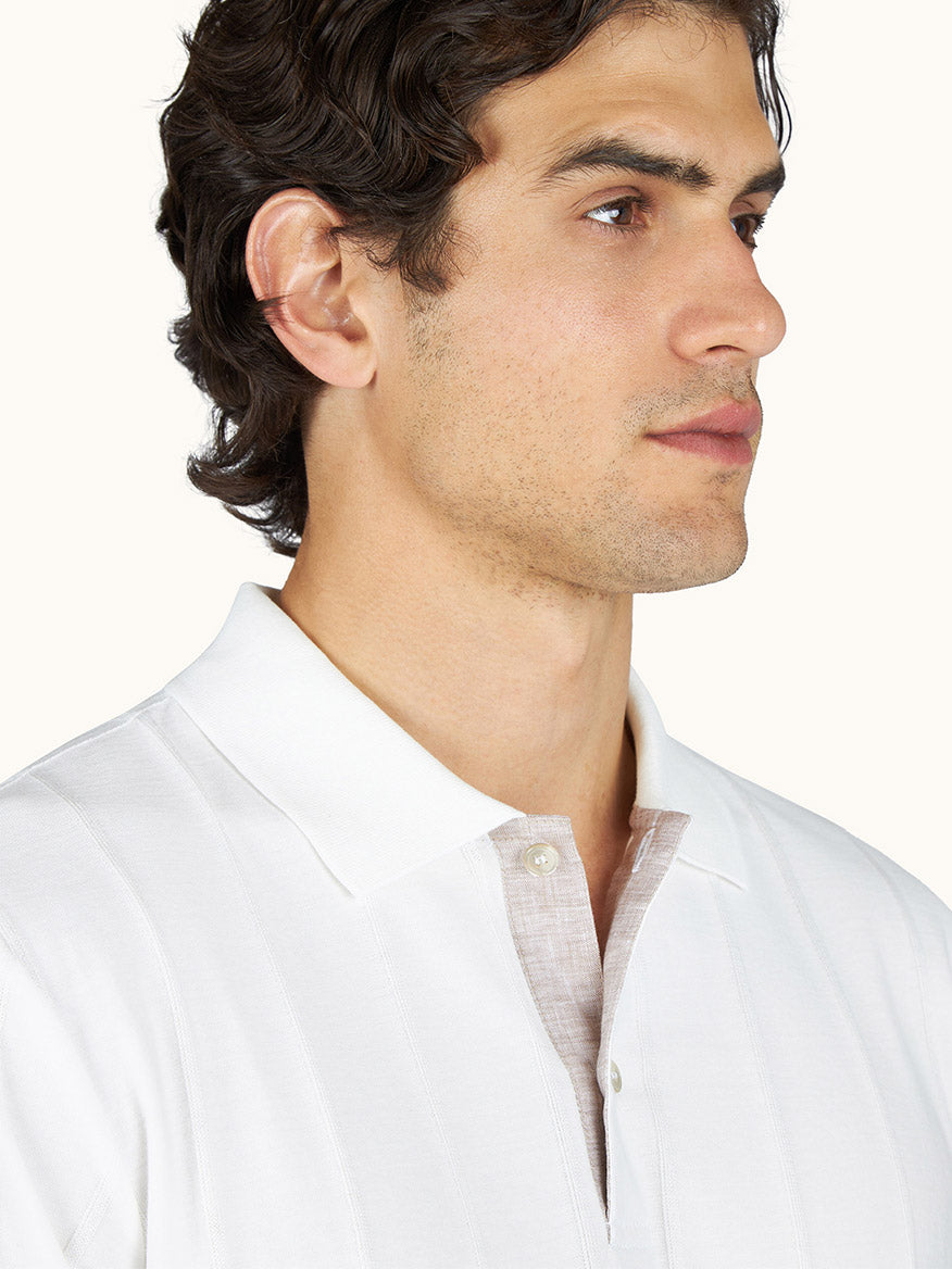 A man with short, dark, curly hair is wearing the Paul & Shark Polo in Piuma Cotton in Blanc de Blanc and looking to the side against a plain background.