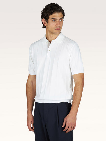 A man wearing a Paul & Shark Polo in Piuma Cotton in Blanc de Blanc and dark trousers stands slightly turned against a plain background.