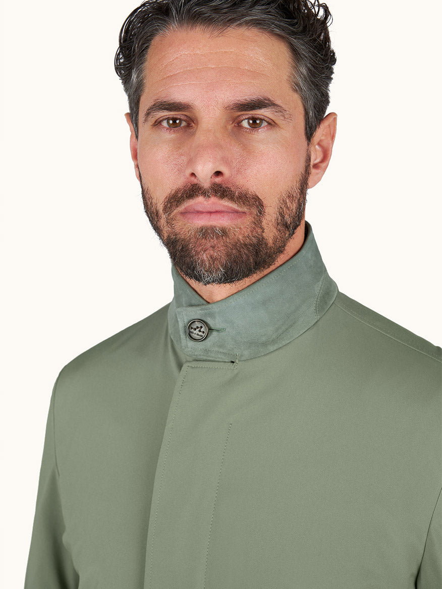 A man with short dark hair and a beard wears a Paul & Shark Typhoon® Platinum Car Coat with Aqualeather suede details in olive, buttoned at the neck, against a plain light background.