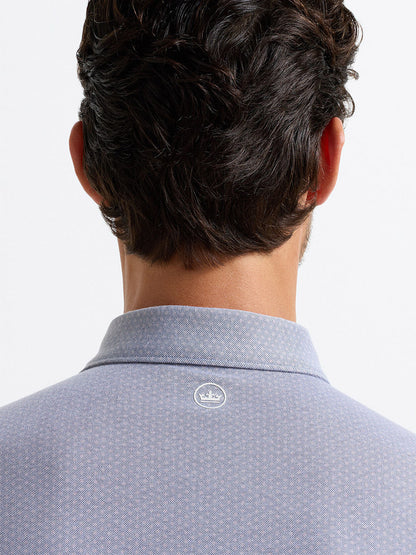 A man is shown from behind wearing the Peter Millar Albatross Diamond Cotton-Blend Piqué Polo in navy, featuring a small white crown logo at the top center of the back.