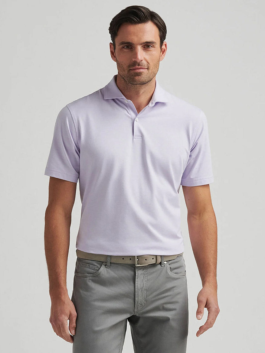 A man wearing the Peter Millar Albatross Cotton Blend Piqué Polo in Lavender Moon and gray pants stands against a plain background.