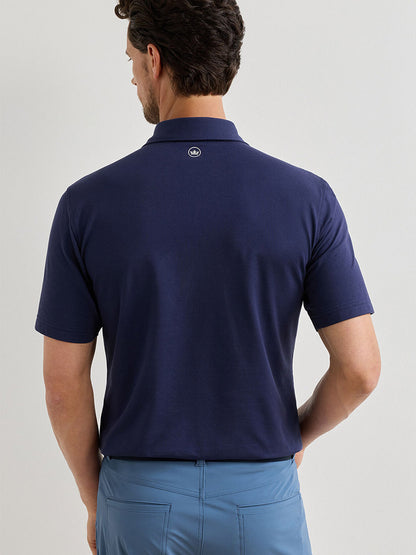 A man with short dark hair is seen from behind, wearing a Peter Millar Albatross Cotton Blend Piqué Polo in navy and light blue pants.