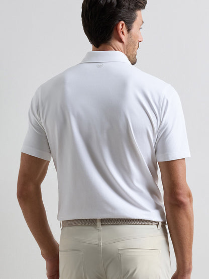 A man wearing a Peter Millar Albatross Cotton Blend Piqué Polo in White and light-colored pants stands facing away from the camera.