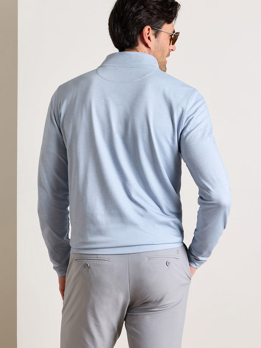 A man, seen from the back against a plain light background, is wearing the Peter Millar Albatross Cotton-Blend Piqué Quarter-Zip in Windy Blue with light gray pants.