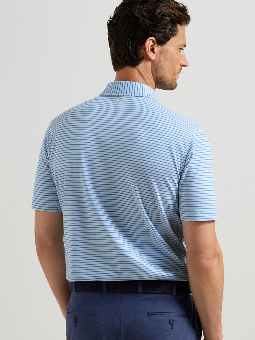 Man wearing the Peter Millar Albatross Stripe Cotton-Blend Piqué Polo in Blue Brisk with navy pants, shown from the back against a plain background.