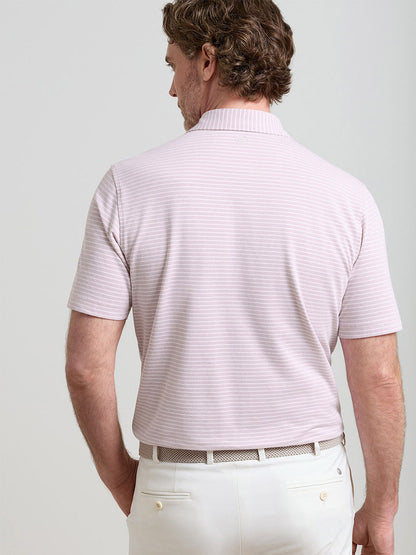 A man is seen from behind, wearing a Peter Millar Albatross Stripe Cotton-Blend Piqué Polo in Faded Scarlet, paired with white pants and a white belt.