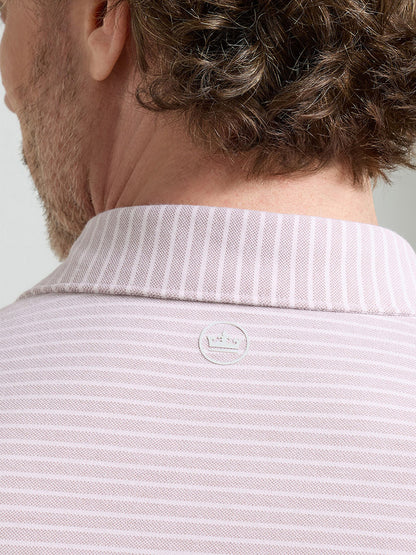 The image shows the back of a man wearing the Peter Millar Albatross Stripe Cotton-Blend Piqué Polo in Faded Scarlet, featuring light pink and white stripes and a small circular logo below the collar.