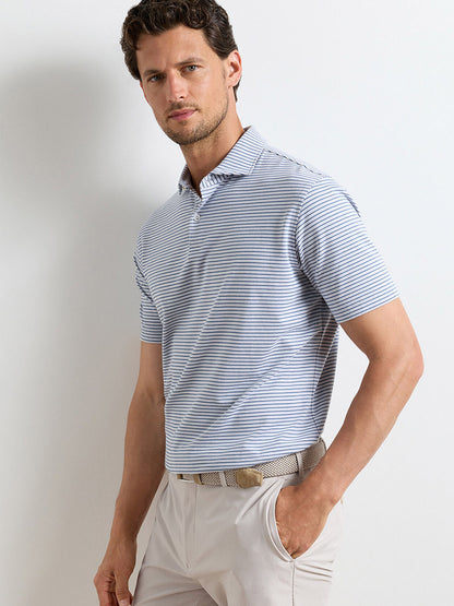 A man stands against a plain white background wearing the Peter Millar Albatross Stripe Cotton-Blend Piqué Polo in Gale Grey, paired with beige pants and a woven belt.