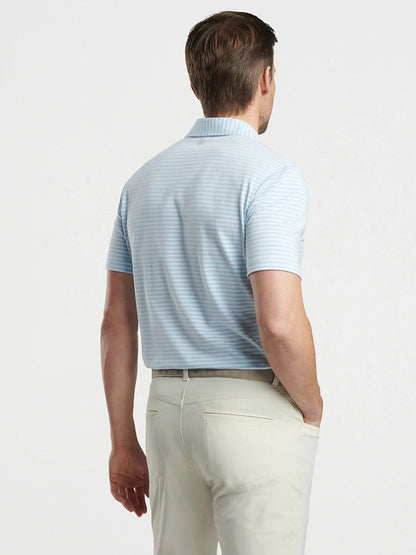 A man wearing a Peter Millar Albatross Stripe Cotton Blend Piqué Polo in Blue Frost and beige pants stands with his back to the camera against a plain background, exuding casual elegance.