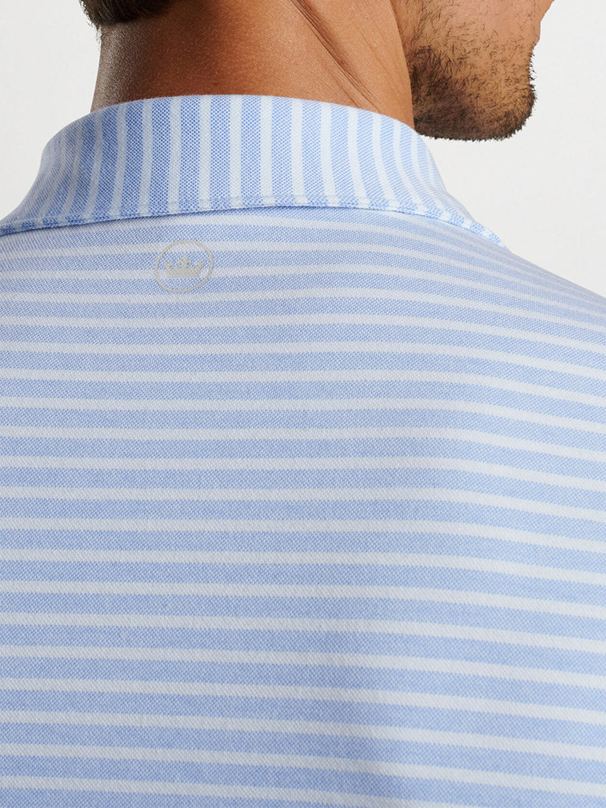 The back view of a man wearing a Peter Millar Albatross Cotton Blend Piqué Striped Polo in Regatta Blue.