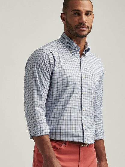 A man in a Peter Millar Albert Crown Lite Cotton-Stretch Sport Shirt in Blue Freesia, crafted from easy-care fabric, with rolled-up sleeves and coral pants stands against a neutral background.