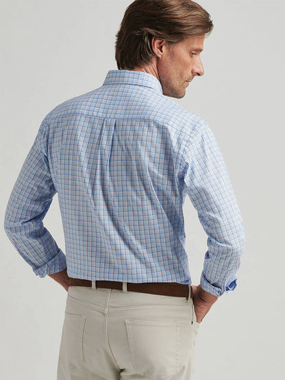 A man in a Peter Millar Albert Crown Lite Cotton-Stretch Sport Shirt in Blue Poppy and beige pants stands with his back to the camera, hands on hips, showcasing a classic fit.