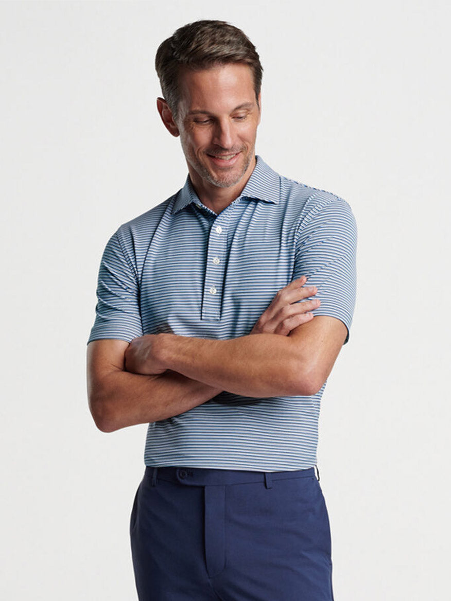Man smiling and standing with arms crossed wearing a Peter Millar Alto Performance Jersey Polo in White/Navy and blue trousers.