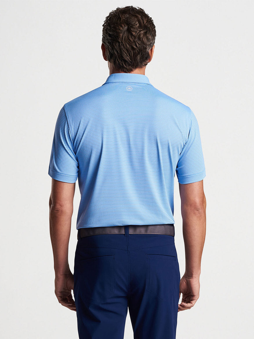 A man viewed from behind wearing a Peter Millar Ambrose Performance Jersey Polo in Regatta Blue and navy pants.