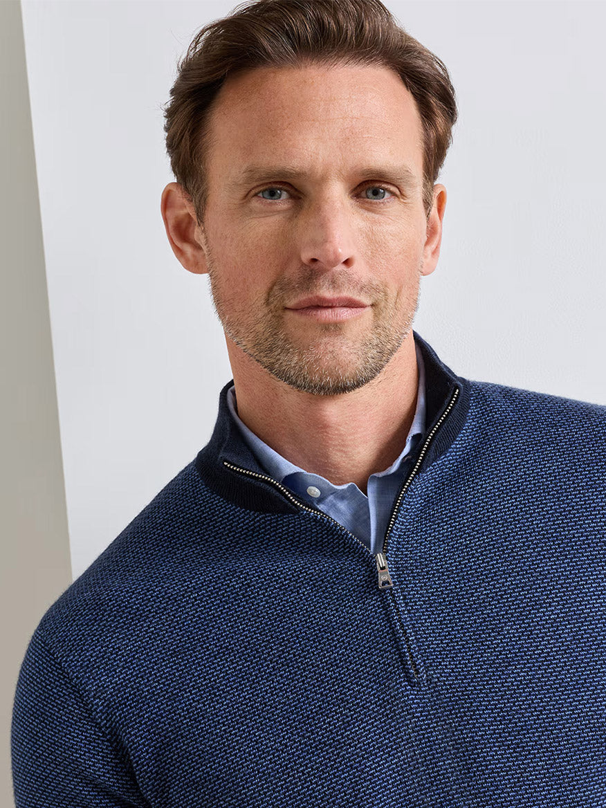 A man with short brown hair and light facial hair wears the Peter Millar Ashland Quarter-Zip Sweater in Midnight Navy, featuring a tailored fit over a collared shirt, looking at the camera against a plain background.