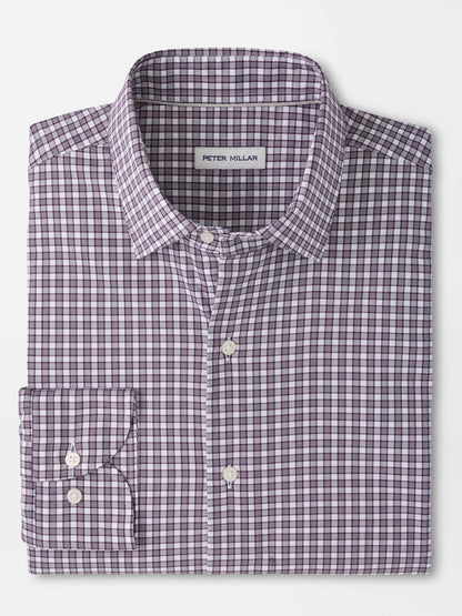 Folded long-sleeve button-up shirt in a purple and white checkered pattern, featuring a front pocket and a visible “Peter Millar” label inside the collar. The Peter Millar Atlas Crown Lite Cotton-Stretch Sport Shirt in Grapeseed is crafted from an easy-care, cotton-stretch twill fabric in a classic fit—perfect for versatile, everyday style.