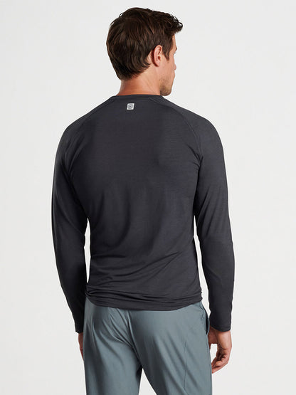 A man from behind wearing a Peter Millar Aurora Performance Long-Sleeve T-Shirt in Black and light gray pants.