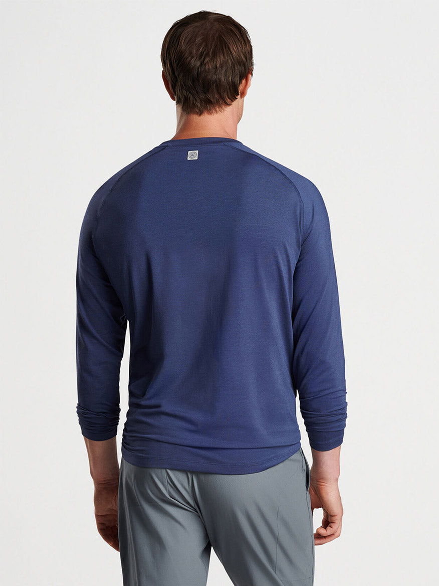 Man wearing a Peter Millar Aurora Performance Long-Sleeve T-shirt in Navy and grey pants, viewed from the back.