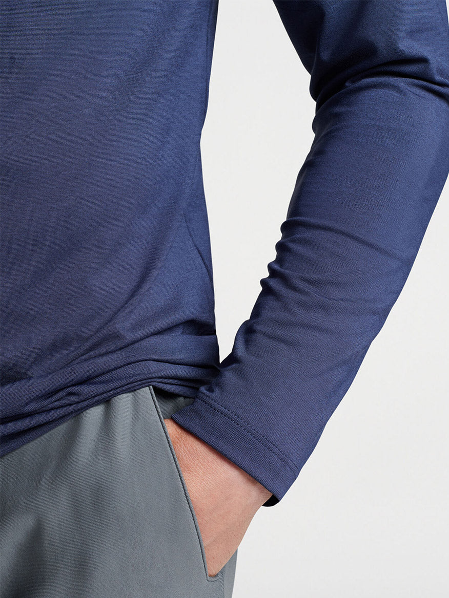Close-up of a person wearing a Peter Millar Aurora Performance Long-Sleeve T-Shirt in Navy tucked into grey pants.