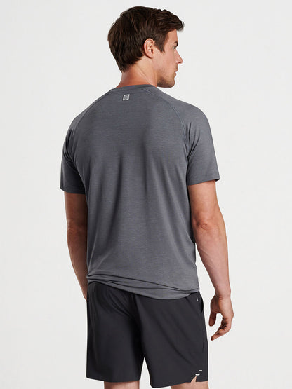 Man from behind wearing a Peter Millar Aurora Performance T-shirt in Iron with UPF 50+ and black shorts standing against a white background.