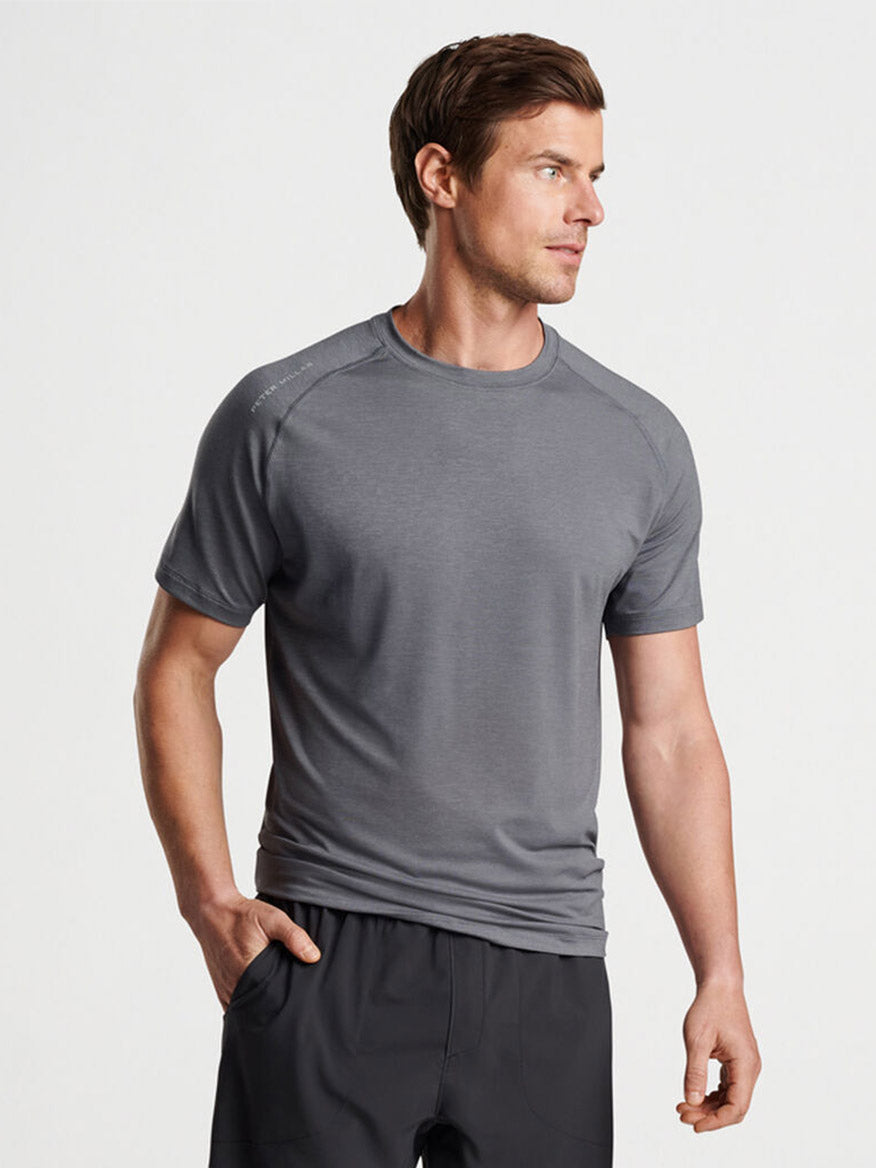 Man modeling a Peter Millar Aurora Performance T-Shirt in Iron and black pants.