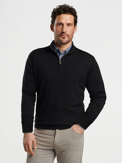 A man with short hair wearing the black Peter Millar Autumn Crest Quarter-Zip sweater and beige pants stands against a plain white background.