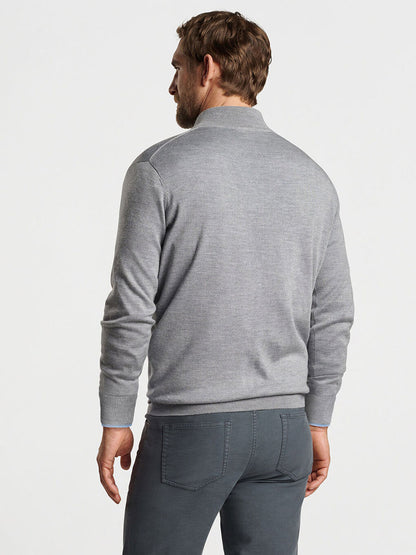 A man with short hair is wearing the Peter Millar Autumn Crest Quarter-Zip in British Grey and dark gray pants, standing and facing away from the camera against a light background. The soft drape of his outfit suggests a lyocell blend, ideal for layering in cooler weather.