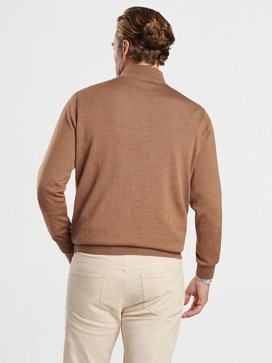 A man with short light brown hair is facing away from the camera, wearing a Peter Millar Autumn Crest Quarter-Zip in British Tan and off-white pants.