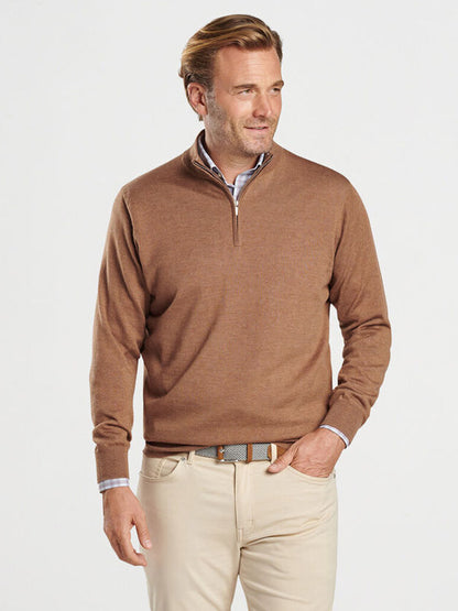 A man wearing a Peter Millar Autumn Crest Quarter-Zip in British Tan, a collared shirt, beige pants, and a brown belt stands against a light background.