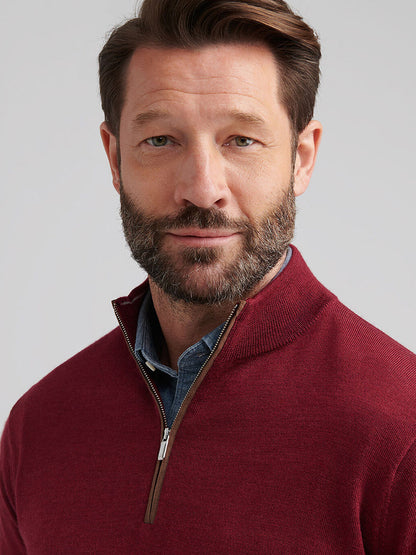 A man with short brown hair and a beard wears the Peter Millar Autumn Crest Suede Trim Quarter-Zip in Brick Red over a blue collared shirt, looking at the camera against a plain background.
