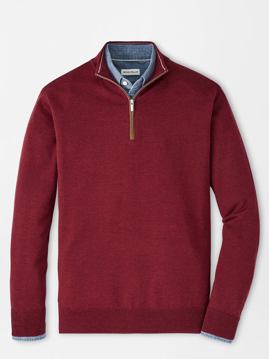 The Peter Millar Autumn Crest Suede Trim Quarter-Zip in Brick Red, featuring a classic fit and brown suede-trimmed zipper, is styled over a blue collared shirt and laid flat on a light background.