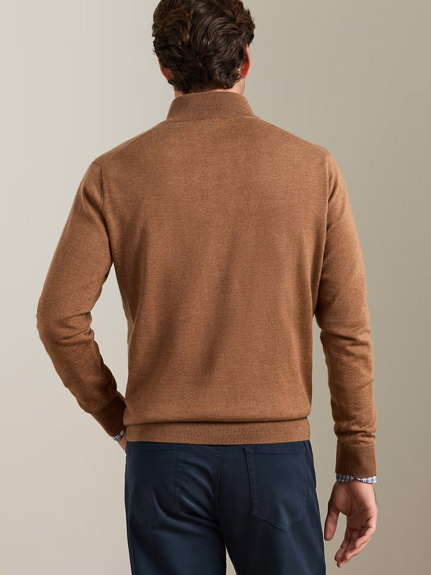 Man wearing the Peter Millar Autumn Crest Suede Trim Quarter-Zip in Dark Amber and navy pants, shown from behind against a plain, light-colored background.