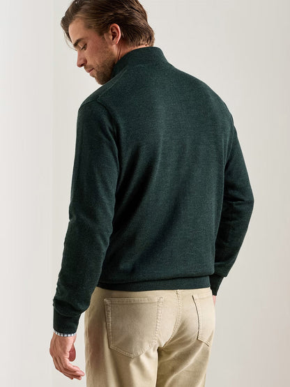 A man stands with his back to the camera, wearing the Peter Millar Autumn Crest Suede Trim Quarter-Zip in Pine Brook and beige pants, set against a neutral background.
