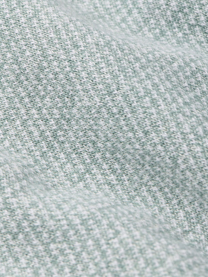 Close-up of the Peter Millar Barlow Quarter-Zip Sweater in Willow, showcasing its soft, light gray and white birdseye jacquard knit with a textured, slightly wavy surface—perfect for making a statement.