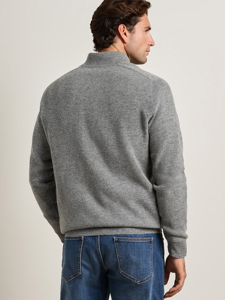 Man seen from the back wearing a Peter Millar Blackburn Button-Mock Sweater in Oslo Grey with blue jeans.