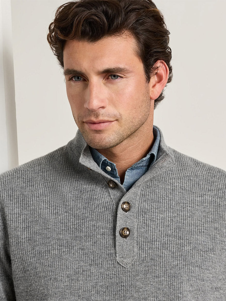 Man wearing a grey Peter Millar Blackburn Button-Mock Sweater in Oslo Grey over a denim shirt.