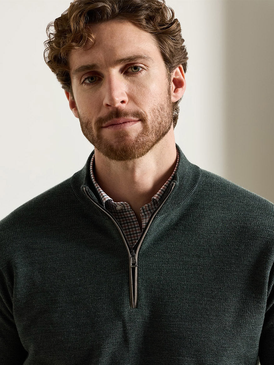 A man wearing a Peter Millar Blair Birdseye Quarter-Zip Sweater in Pine Brook over a patterned collared shirt.