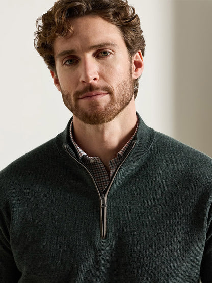 A man wearing a Peter Millar Blair Birdseye Quarter-Zip Sweater in Pine Brook over a patterned collared shirt.