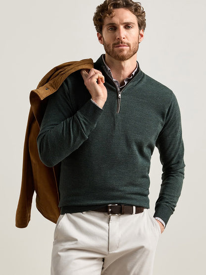 A man wearing a Peter Millar Blair Birdseye Quarter-Zip Sweater in Pine Brook over a plaid button-down shirt, with a tan jacket draped over his shoulder.