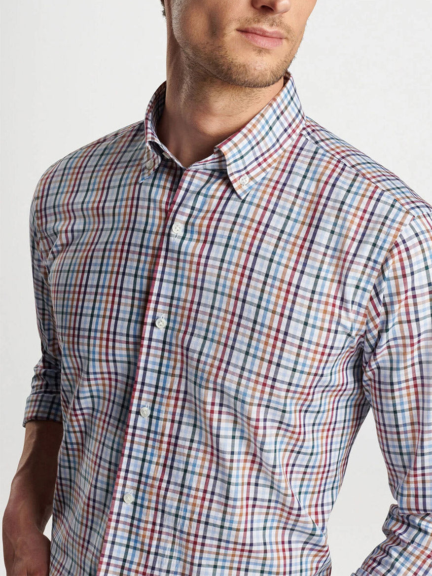 A man wearing the Peter Millar Brighton Cotton Sport Shirt in Navy, a checkered long-sleeve shirt with a collar, stands against a plain background, facing slightly to the right.