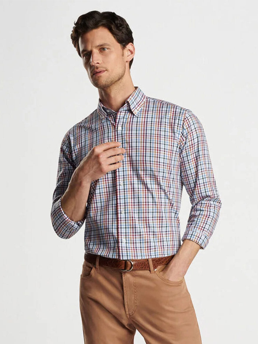 A man wearing a tailored fit Peter Millar Brighton Cotton Sport Shirt in Navy and beige pants poses with one hand touching his collar and the other in his pocket against a plain white background, showcasing Flex Finish technology.