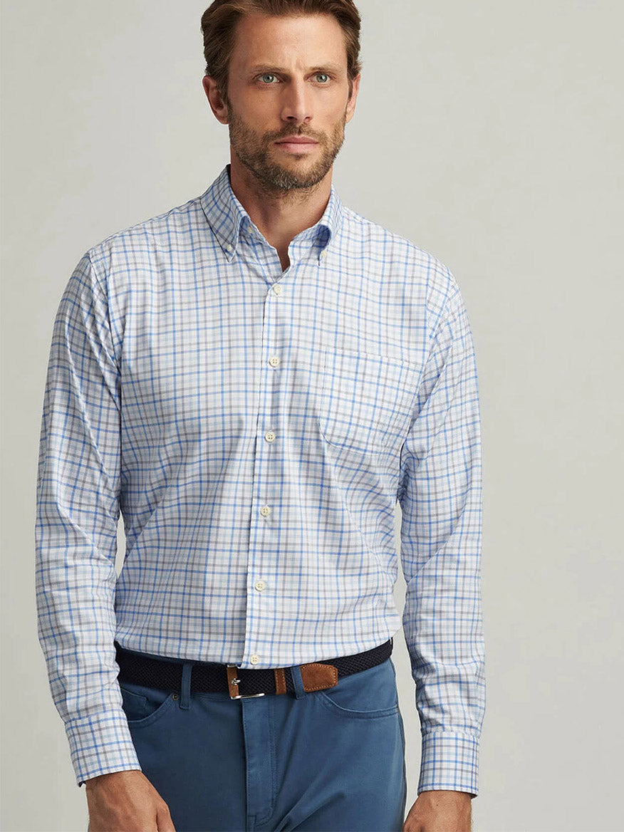 A man in a blue Peter Millar Calgary Crown Lite Cotton-Stretch Sport Shirt and matching blue pants stands against a neutral background.