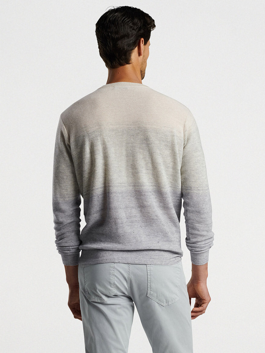 Man viewed from behind wearing a Peter Millar Camden High V Striped Sweater in British Grey and light gray pants against a white background.