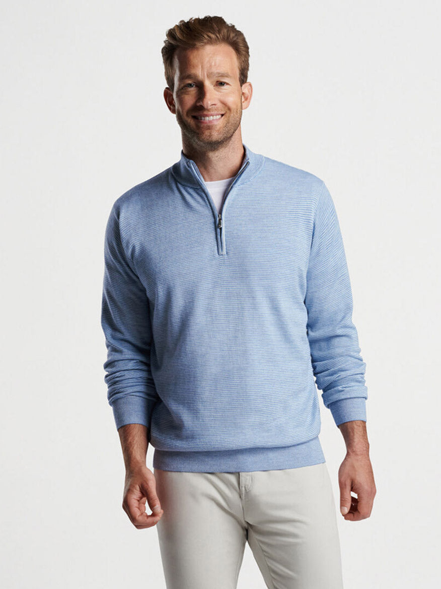 Man smiling in a studio, wearing a Peter Millar Canton Stripe Quarter-Zip Sweater in Cottage Blue and beige pants.