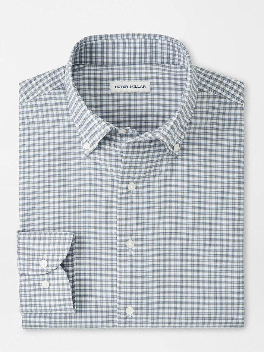 A neatly folded Peter Millar Cashiers Performance Twill Sport Shirt in Oslo Grey, featuring long sleeves, a button-up front, and a blue and white checkered pattern with the label on the inside collar.