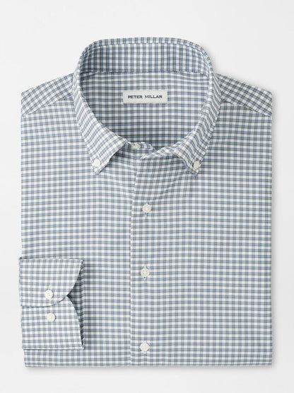 A neatly folded Peter Millar Cashiers Performance Twill Sport Shirt in Oslo Grey, featuring long sleeves, a button-up front, and a blue and white checkered pattern with the label on the inside collar.