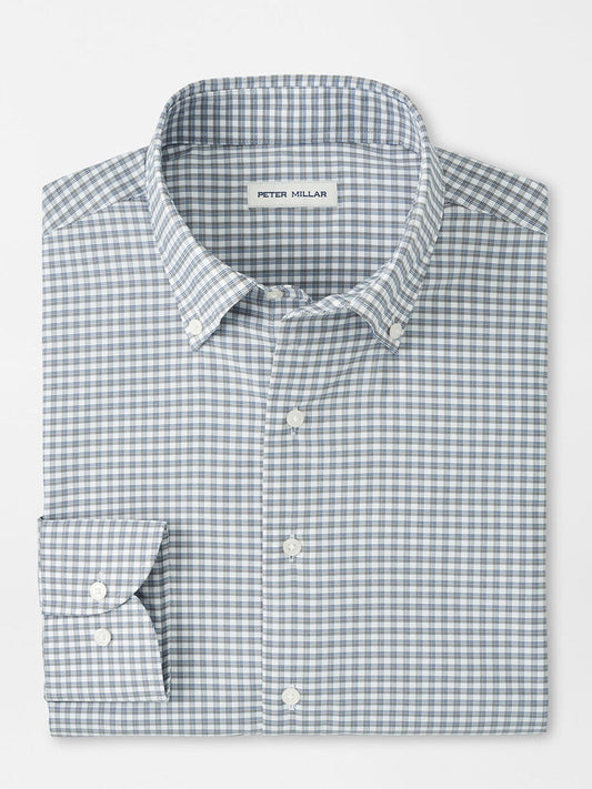 A neatly folded Peter Millar Cashiers Performance Twill Sport Shirt in Oslo Grey, featuring long sleeves, a button-up front, and a blue and white checkered pattern with the label on the inside collar.