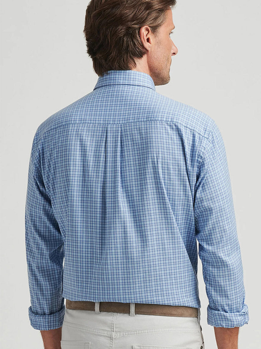 A man with brown hair wears a Peter Millar Caspian Perfect Pinpoint Cotton-Stretch Sport Shirt in Blue Freesia and light-colored pants, facing away.